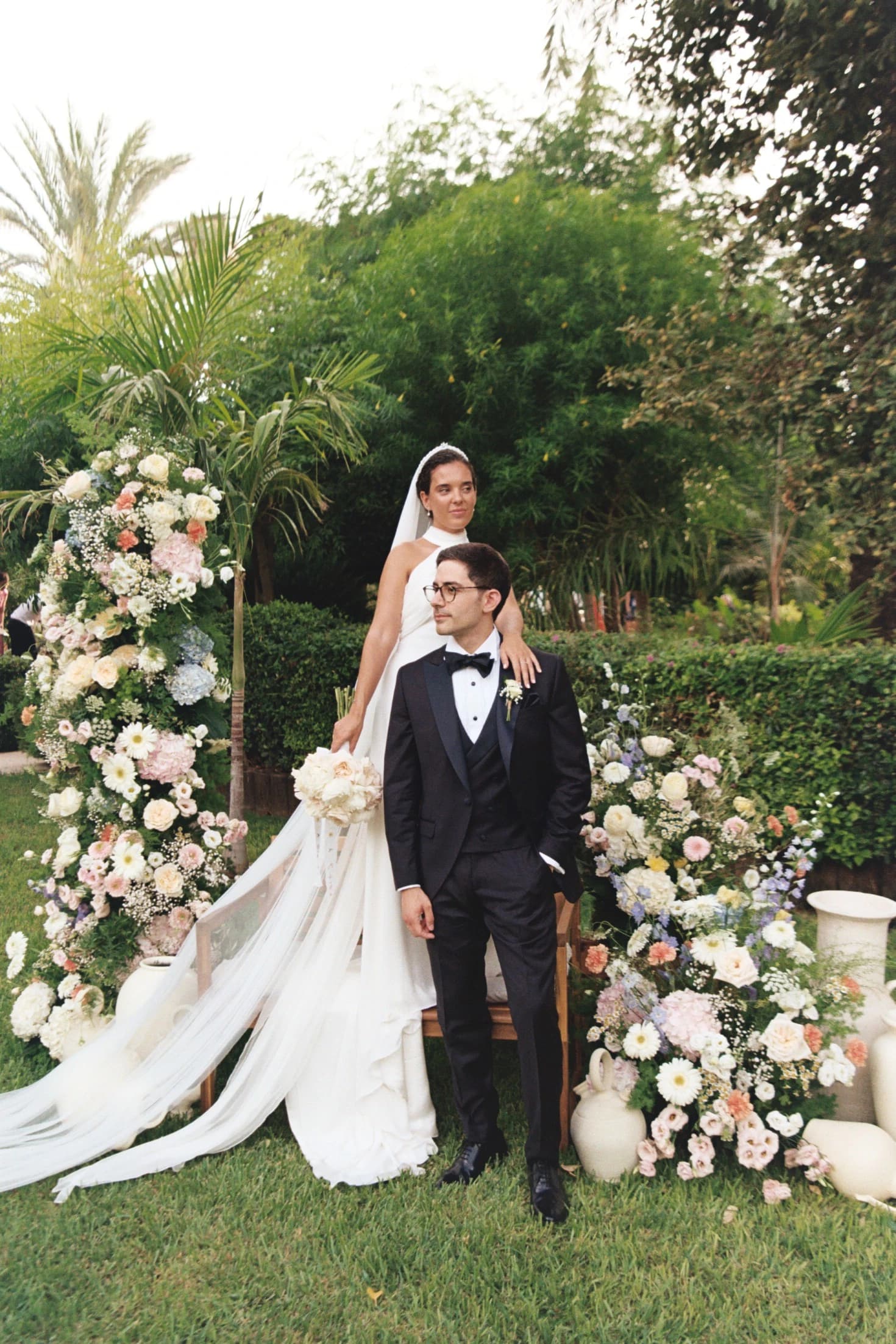 Novios en un jardín rodeado de flores