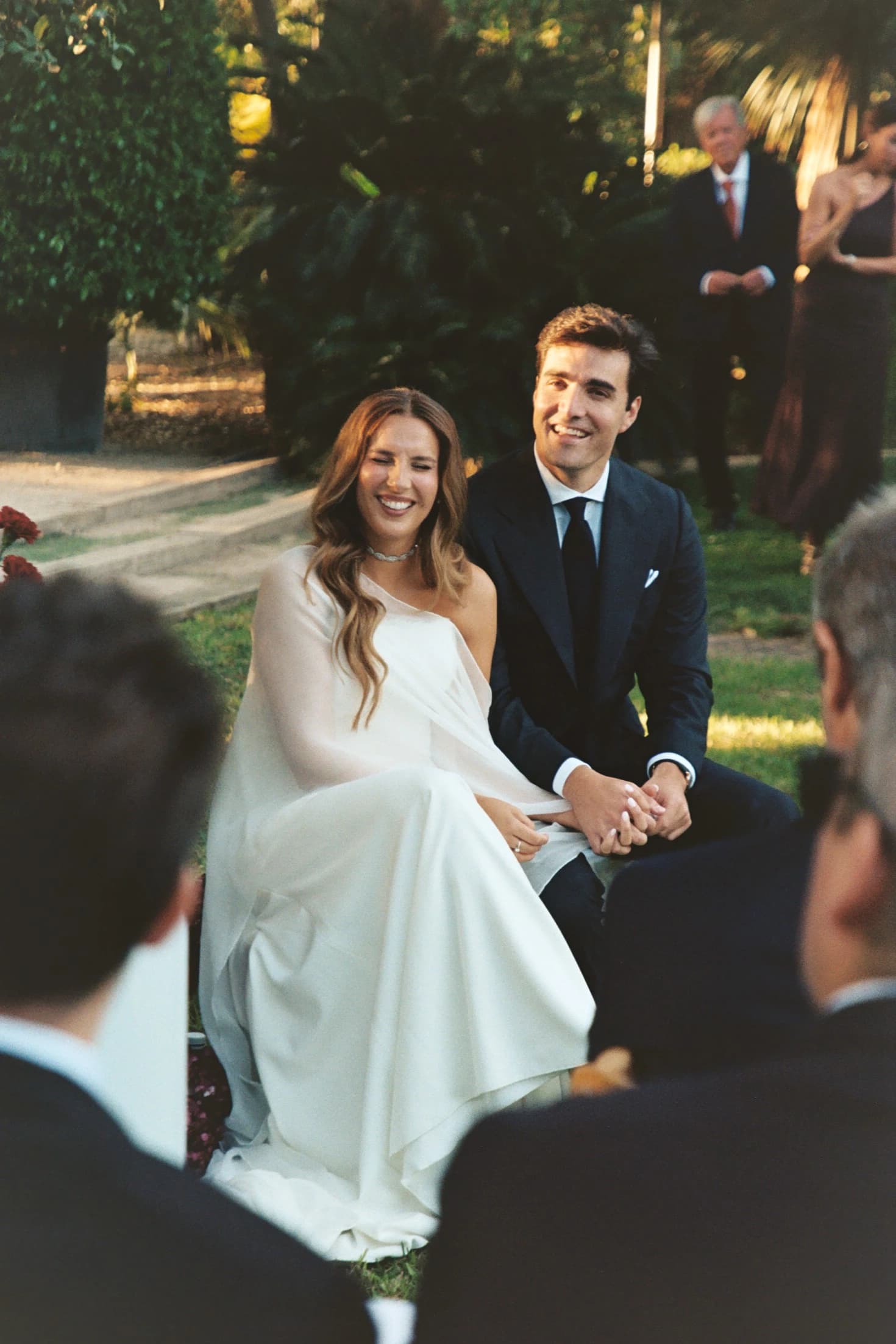 Novios celebrando sentados entre los invitados