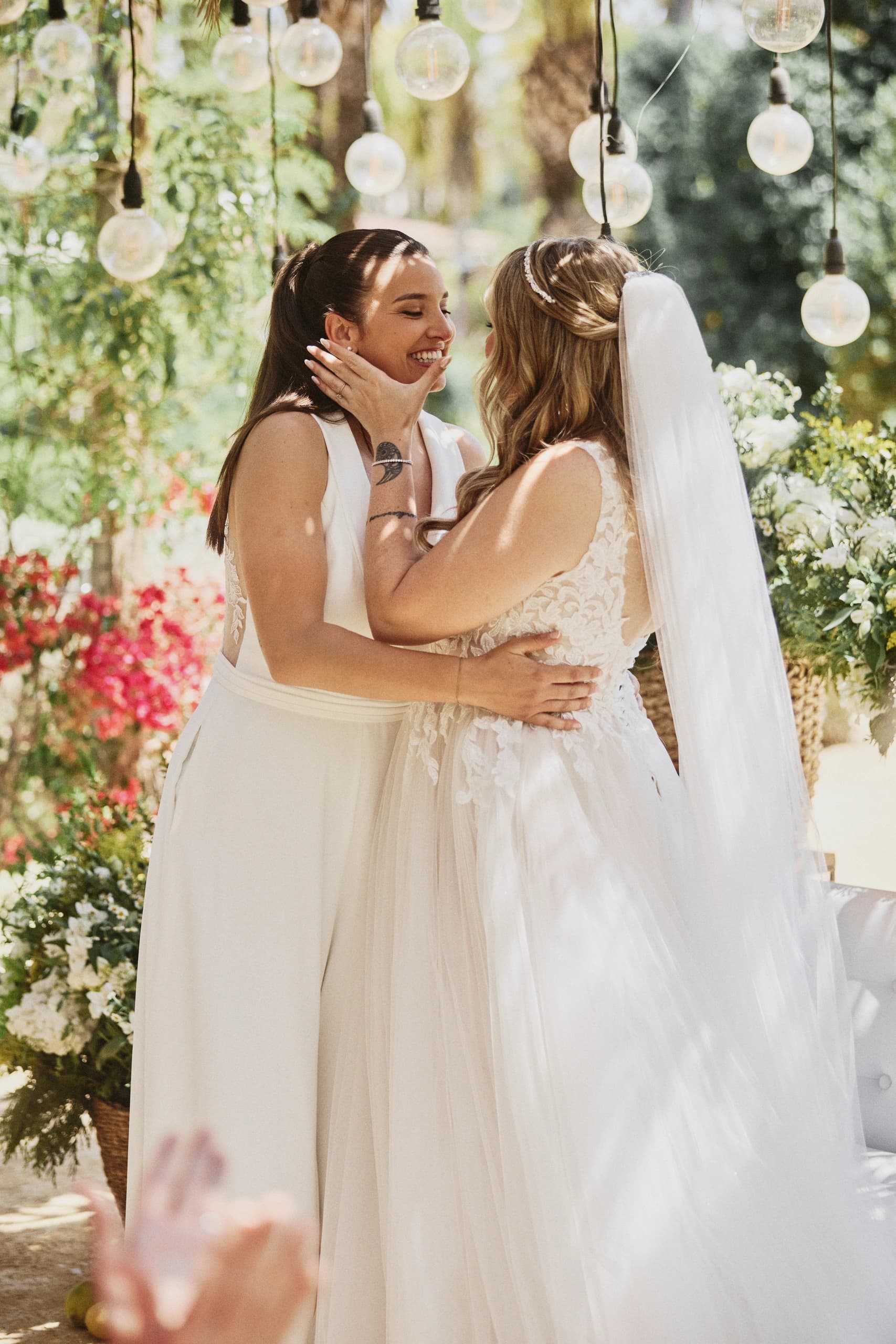 Dos novias abrazadas bajo luces colgantes